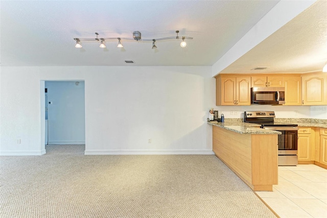 kitchen with light stone countertops, appliances with stainless steel finishes, light brown cabinets, light tile floors, and rail lighting