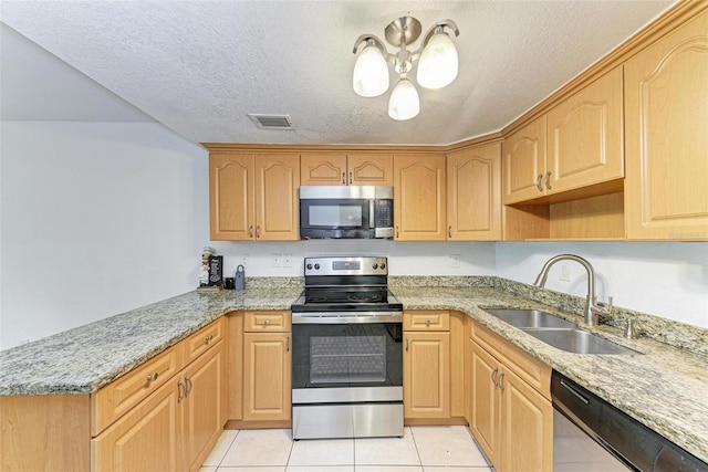 kitchen with light tile floors, light stone countertops, a textured ceiling, appliances with stainless steel finishes, and sink