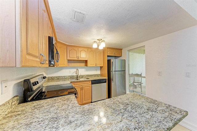 kitchen featuring kitchen peninsula, light stone countertops, appliances with stainless steel finishes, sink, and a textured ceiling