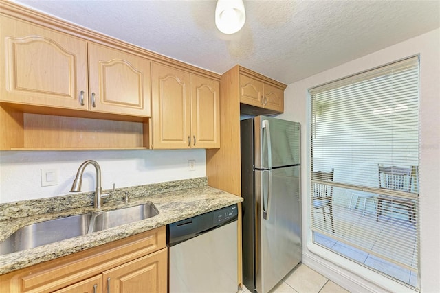 kitchen featuring appliances with stainless steel finishes, sink, light tile floors, a textured ceiling, and light stone counters