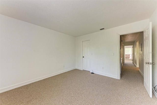 carpeted empty room featuring a textured ceiling