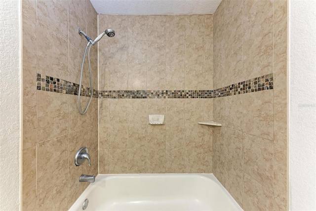 bathroom featuring tiled shower / bath and a textured ceiling