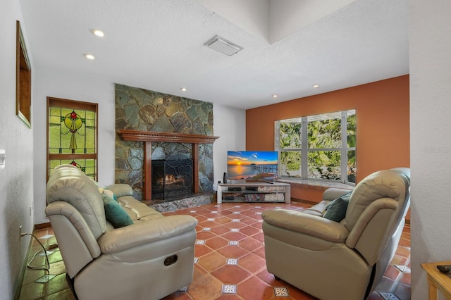 living room featuring a textured ceiling, tile floors, and a stone fireplace