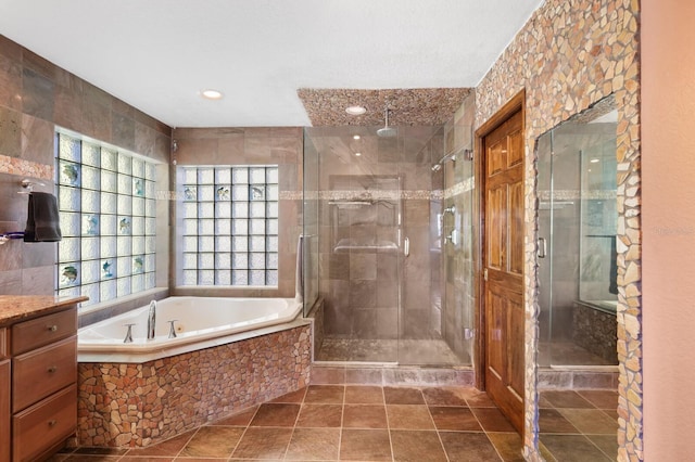 bathroom with tile walls, separate shower and tub, tile floors, and vanity