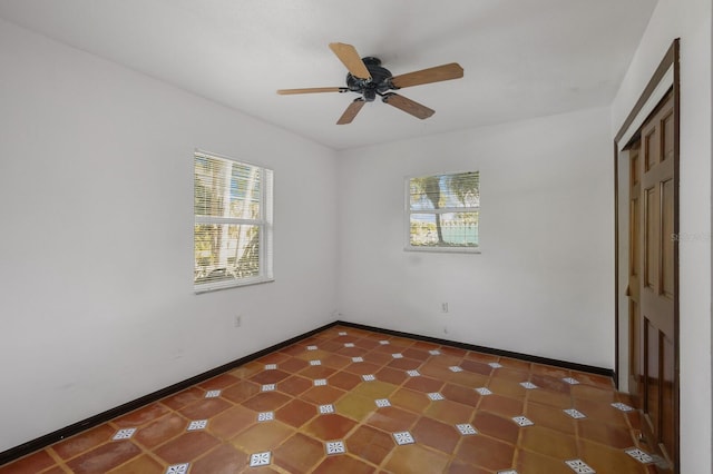 unfurnished bedroom with dark tile floors, multiple windows, and ceiling fan