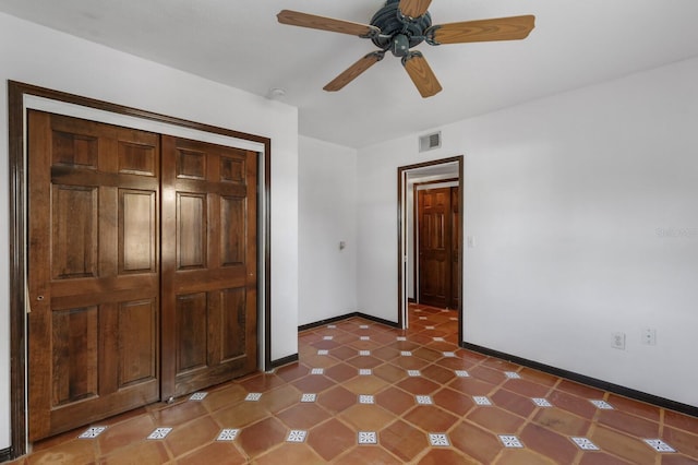 unfurnished bedroom featuring a closet, ceiling fan, and dark tile floors