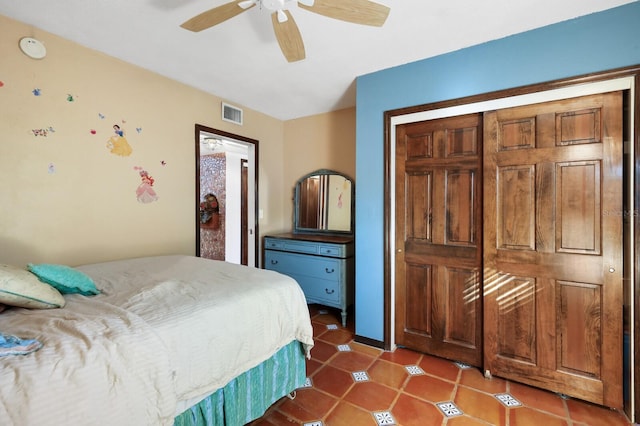 bedroom with a closet, dark tile floors, and ceiling fan