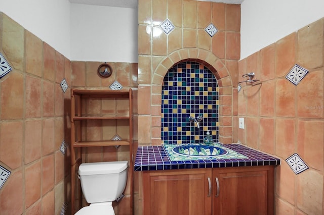 bathroom featuring vanity, toilet, and tile walls