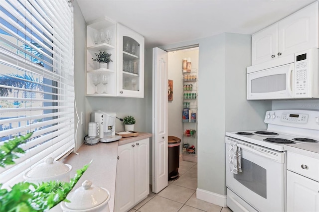 kitchen with a wealth of natural light, white cabinets, white appliances, and light tile floors