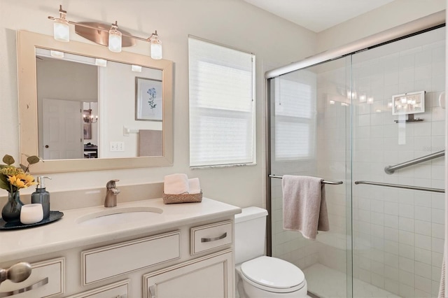 bathroom with vanity, toilet, a healthy amount of sunlight, and walk in shower