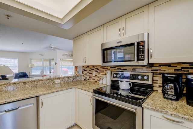 kitchen featuring ceiling fan, light stone counters, white cabinets, backsplash, and stainless steel appliances