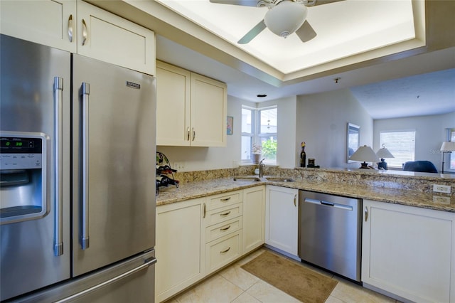 kitchen with ceiling fan, sink, stainless steel appliances, light tile floors, and light stone counters