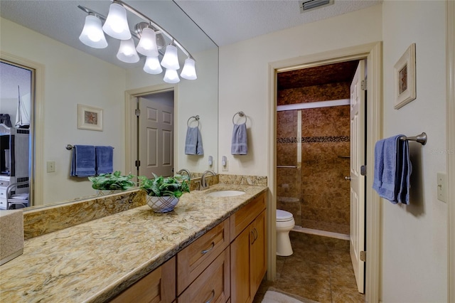 bathroom featuring toilet, a shower with door, a textured ceiling, vanity with extensive cabinet space, and tile flooring