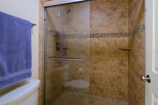 bathroom featuring a shower with door and toilet