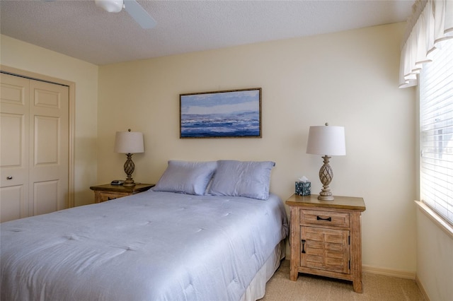 carpeted bedroom with a closet, a textured ceiling, and ceiling fan