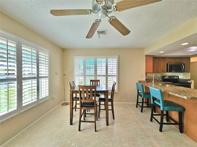 tiled dining room featuring a textured ceiling, ceiling fan, and sink