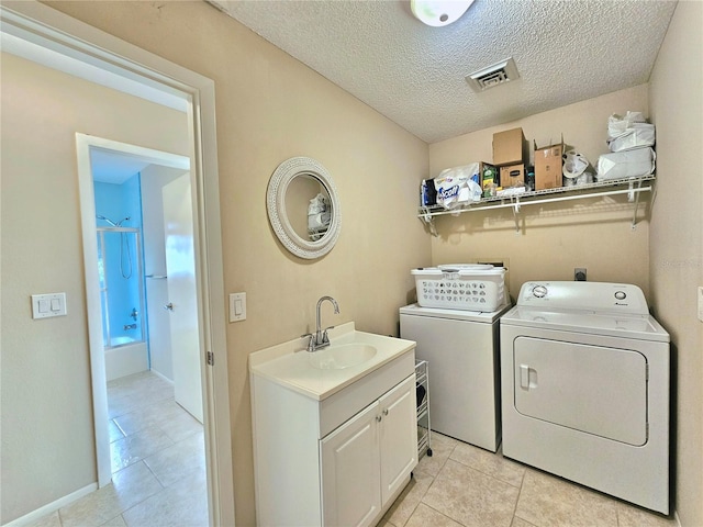 washroom with washer and dryer, light tile floors, a textured ceiling, and sink