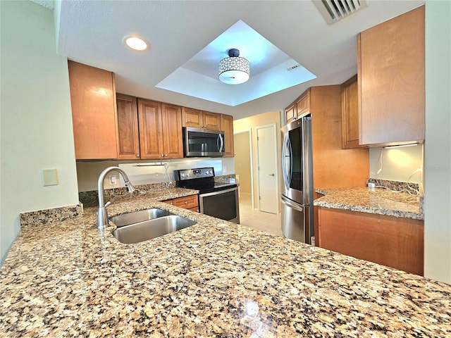 kitchen featuring sink, light tile floors, a raised ceiling, stainless steel appliances, and light stone countertops