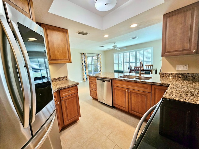 kitchen featuring dark stone countertops, appliances with stainless steel finishes, ceiling fan, and light tile floors