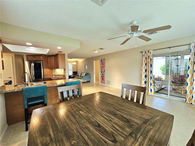 dining space featuring light tile floors, a textured ceiling, ceiling fan, and sink