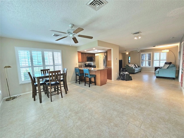 dining space featuring a textured ceiling, ceiling fan, and light tile floors