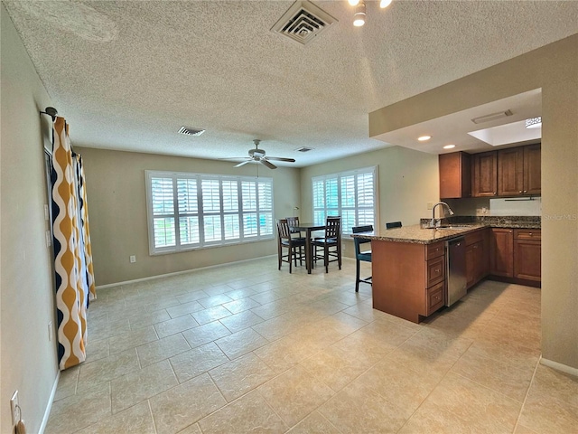 kitchen featuring kitchen peninsula, ceiling fan, light tile flooring, sink, and dark stone counters