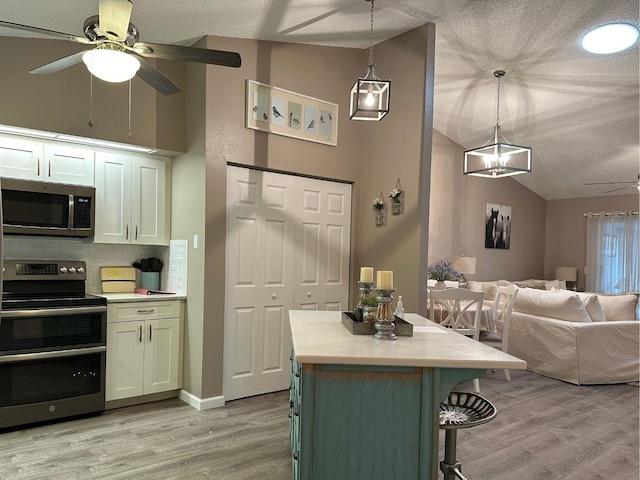 kitchen with light hardwood / wood-style flooring, backsplash, ceiling fan with notable chandelier, and stainless steel appliances