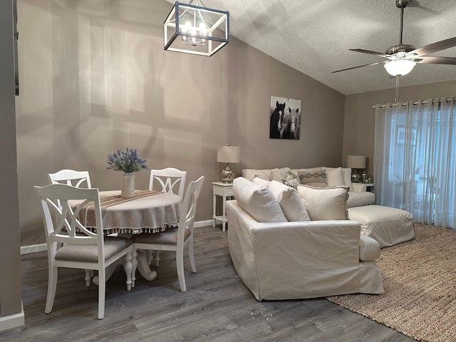 interior space with a textured ceiling, vaulted ceiling, ceiling fan with notable chandelier, and dark hardwood / wood-style flooring