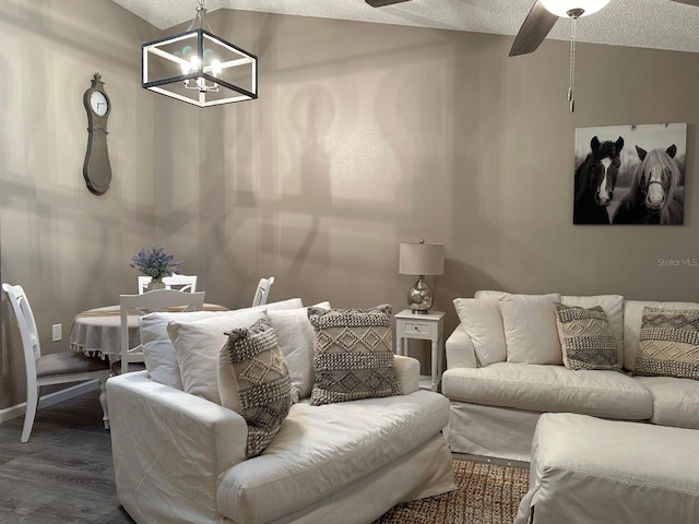 living room with dark wood-type flooring, a textured ceiling, and ceiling fan with notable chandelier