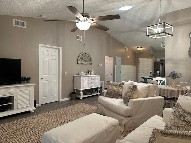 living room featuring a textured ceiling, dark wood-type flooring, high vaulted ceiling, and ceiling fan with notable chandelier