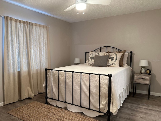 bedroom with ceiling fan, a textured ceiling, and dark wood-type flooring