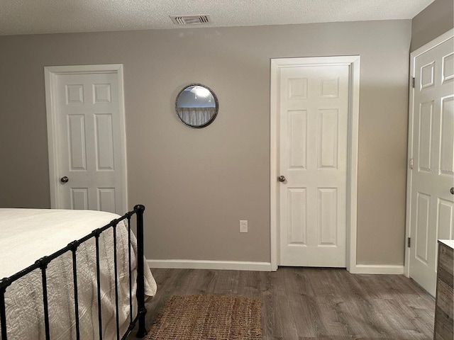 unfurnished bedroom featuring a textured ceiling and dark hardwood / wood-style flooring