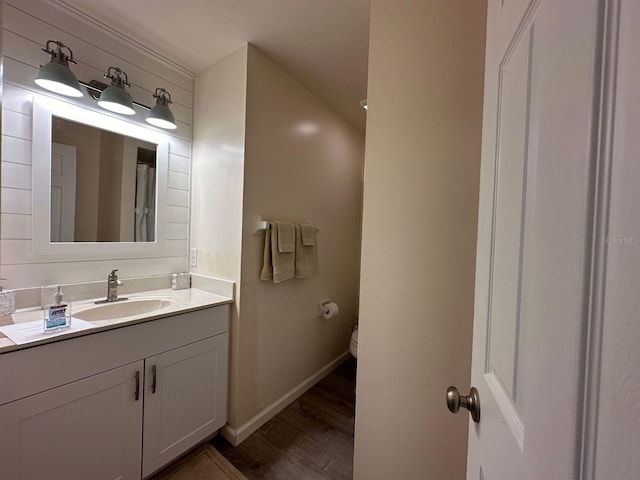 bathroom featuring toilet, vanity with extensive cabinet space, and hardwood / wood-style flooring