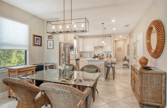 dining space featuring light tile floors, a notable chandelier, and sink