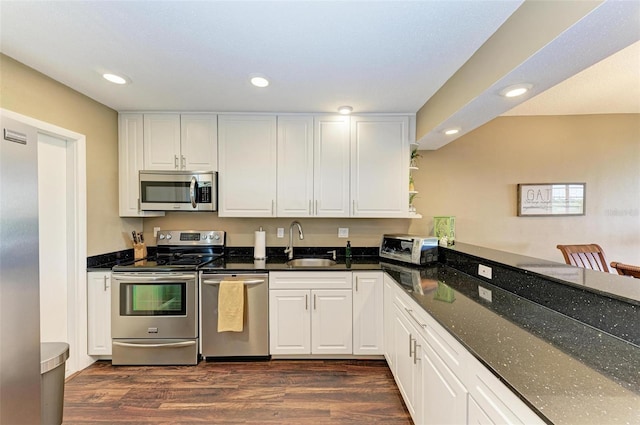 kitchen featuring white cabinetry, dark wood-type flooring, sink, stainless steel appliances, and dark stone countertops