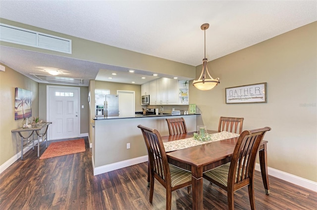 dining room with a textured ceiling and dark hardwood / wood-style flooring