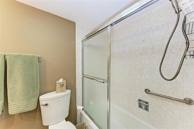 bathroom with toilet and bath / shower combo with glass door