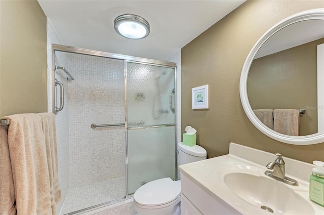 bathroom with vanity, a shower with door, and toilet