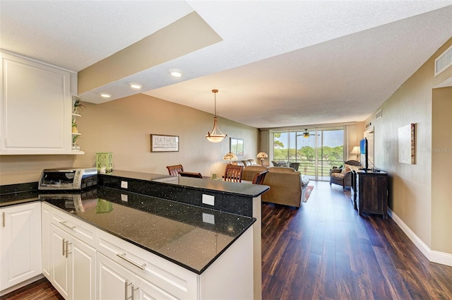 kitchen featuring kitchen peninsula, ceiling fan, white cabinets, and dark wood-type flooring