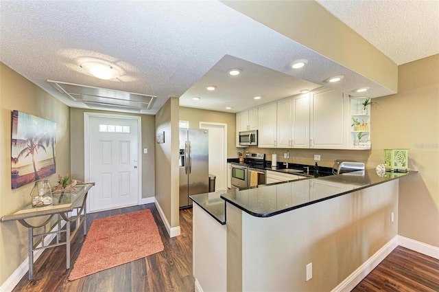 kitchen featuring white cabinets, kitchen peninsula, dark wood-type flooring, and stainless steel appliances