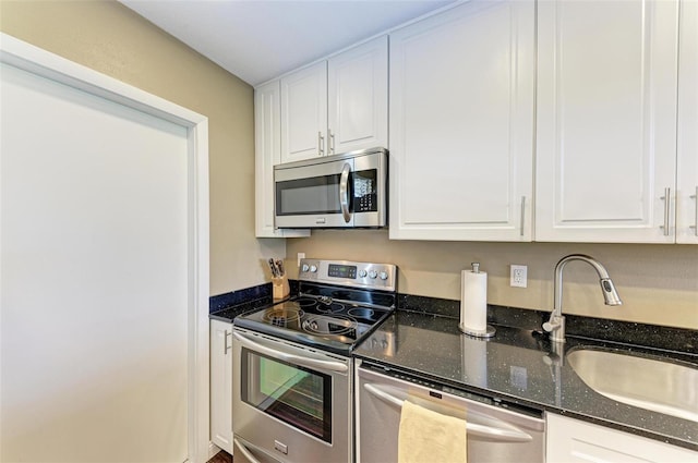 kitchen featuring dark stone counters, white cabinetry, sink, and stainless steel appliances