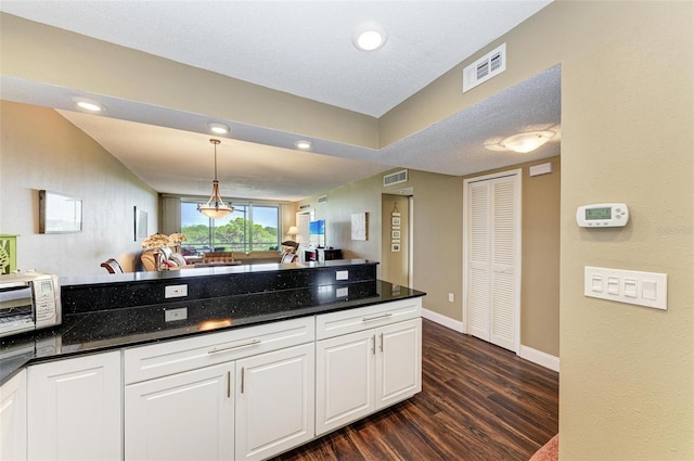 kitchen featuring pendant lighting, dark stone countertops, white cabinetry, and dark hardwood / wood-style flooring