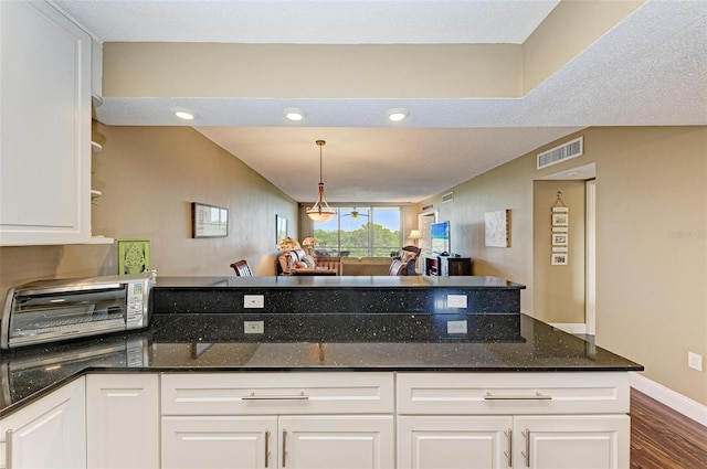 kitchen featuring white cabinetry, dark wood-type flooring, dark stone countertops, a chandelier, and pendant lighting