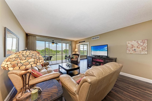 living room featuring dark wood-type flooring, a textured ceiling, and ceiling fan