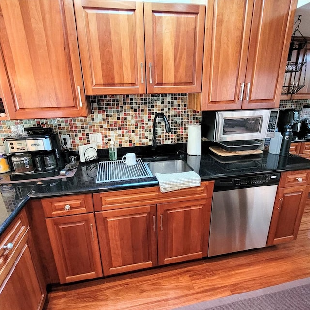 kitchen featuring dark stone counters, light hardwood / wood-style floors, appliances with stainless steel finishes, and sink