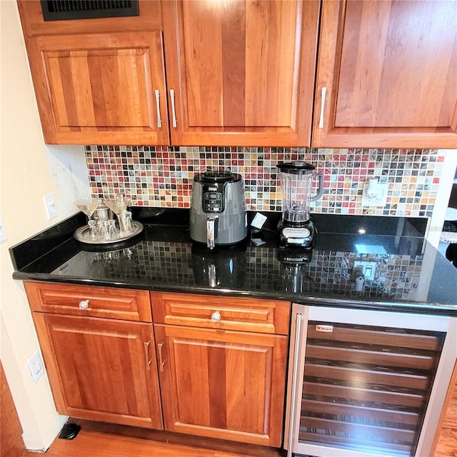 interior space with light wood-type flooring, beverage cooler, tasteful backsplash, and dark stone countertops