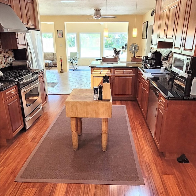 kitchen with kitchen peninsula, backsplash, ceiling fan, appliances with stainless steel finishes, and tile floors