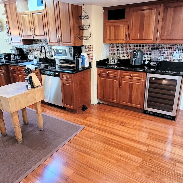 kitchen featuring wine cooler, light hardwood / wood-style flooring, appliances with stainless steel finishes, backsplash, and sink