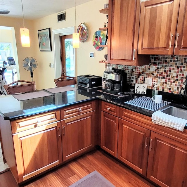 kitchen with hardwood / wood-style floors, kitchen peninsula, backsplash, sink, and pendant lighting