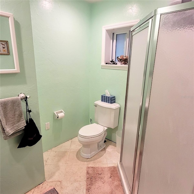 bathroom with toilet, tile floors, and a shower with shower door